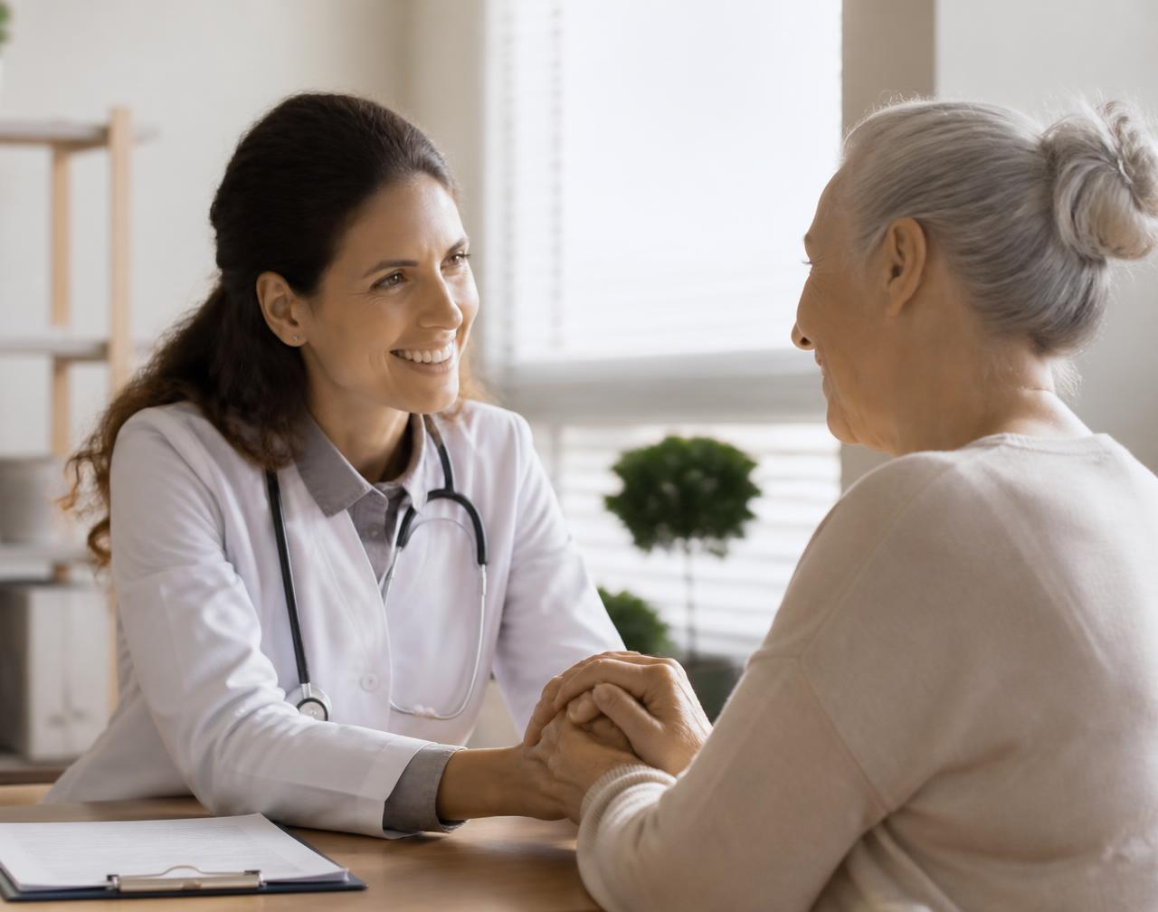 Médica acolhendo paciente idosa durante consulta